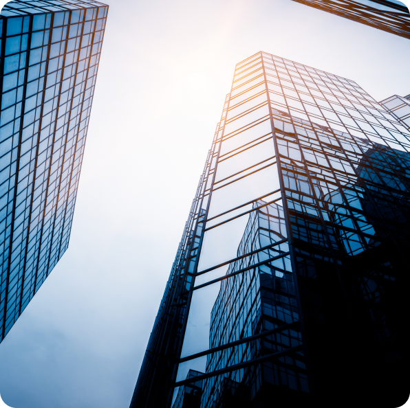 Low-angle view of glass office towers reaching into a bright sky