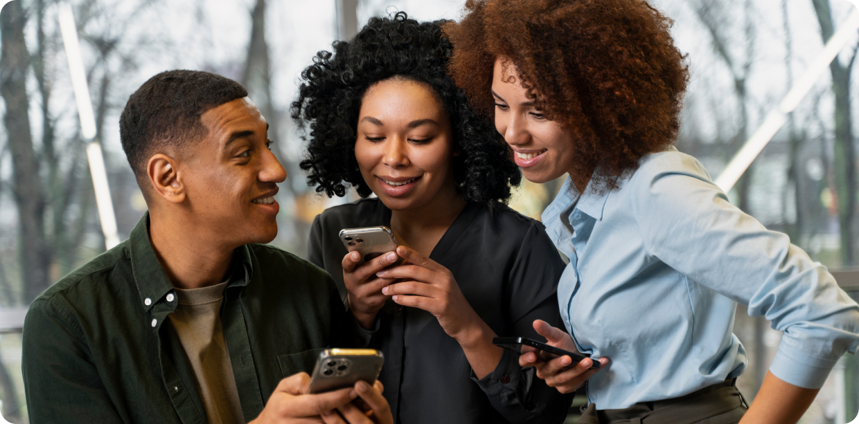 Three friends looking at their phones together and smiling